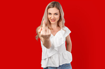 Portrait of annoyed young woman showing middle finger isolated on color background