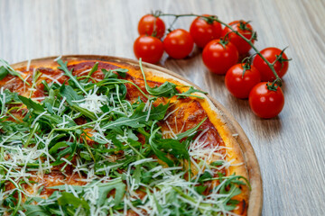 pizza with ham, arugula, tomato sauce and shredded mozzarella