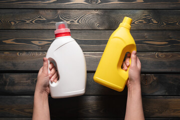 Two detergent bottles in female hands close up. Top view.