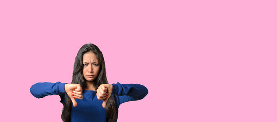 Upset frowning young woman showing double thumb down
