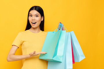 Portrait Asian beautiful young woman in a yellow T-shirt with multicolored shopping bags studio model unaltered