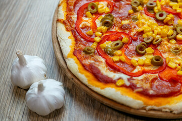 pizza with mozzarella, green olive, salami, corn and red pepper
