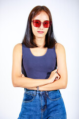 Portrait isolated closeup studio cutout shot of Asian female model in crop top shirt jeans and sunglasses smiling look at camera on white background