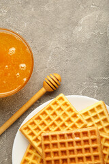 Belgian waffles on white platewith honey. Vertical photo.