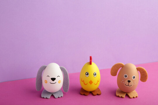 Easter holiday concept with cute handmade eggs, dogs, chicks and cat on purple background.