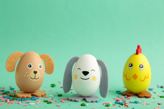 Easter holiday concept with cute handmade eggs, dogs, chicks and cat on mint background.