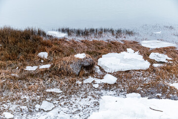 snow and big chunks of ice covering the grassy river band during the winter