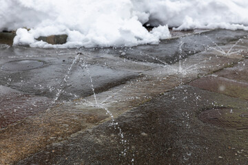 雪が積もった駐車場と水が噴き出す消雪設備