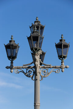 Classic black metallic candelabra street light lamppost with five lamps close up on a blue sky background