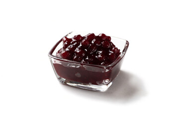 Lingonberry jam in a glass saucepan on a white background. Cranberry berries in a glass saucepan