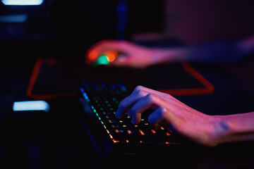 Gamer play computer game, use rgb neon colored keyboard
