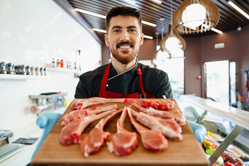 Young butcher holding raw lamb ribs in a butcher shop © fotofabrika