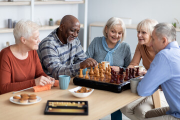 Multiracial senior people playing chess at nursing home
