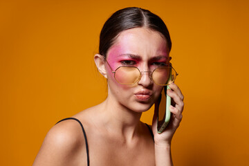Portrait of beautiful young woman with glasses bright makeup posing black jersey talking on the phone close-up unaltered
