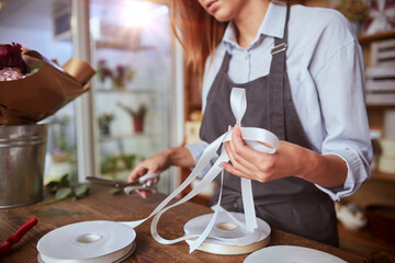 Florist finishing wrapping fresh bouquet with ribbon