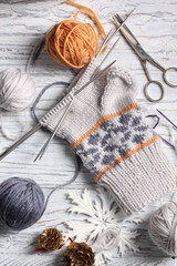 Flat lay of knitting and winter accessories on white background