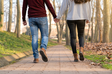 Young heterosexual couple walking and hugging in a park on valentine's day