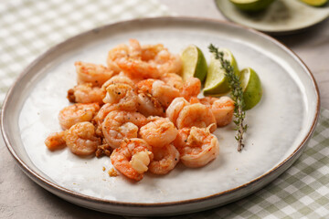 Grilled shrimps or tiger prawns served with lime, garlic and fresh herbs on scandi round plate on concrete surface. Pescatarian protein nutrition