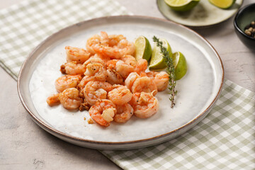 Grilled shrimps or tiger prawns served with lime, garlic and fresh herbs on scandi round plate on concrete surface. Pescatarian protein nutrition