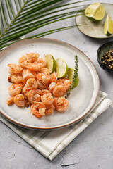 Grilled shrimps or tiger prawns served with lime, garlic and fresh herbs on scandi round plate on concrete surface. Pescatarian protein nutrition
