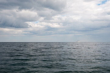 Obraz premium Black Sea coastline in southern Crimea with a sailing boat in the background under the cloudy sky, Russia