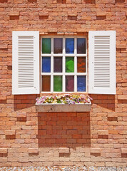 White window with flower pots on the brick wall.