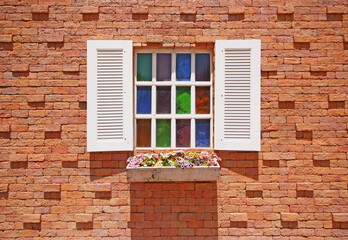 Fototapeta na wymiar White window with flower pots on the brick wall.