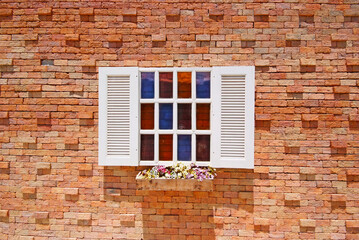 Fototapeta na wymiar White window with flower pots on the brick wall.