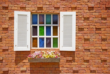 Fototapeta na wymiar White window with flower pots on the brick wall