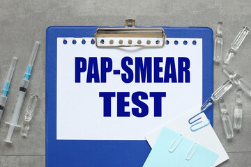 PAP-SMEAR TEST text on white paper on a blue folder with a clip near syringes and ampoules