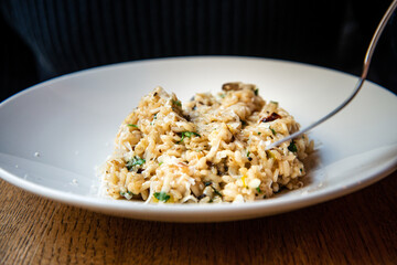 Delicious Italian vegetarian risotto cooked with mushrooms and onions served in white plate.