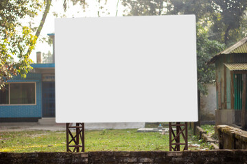 A big white signboard attaches two iron poles and the background blur behind it.