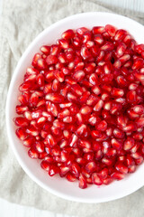 Red Pomegranate Seeds in a White Bowl , top view. Flat lay, overhead, from above.