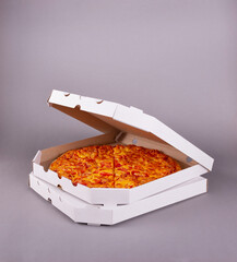 Two fragrant tasty pizzas in a box on gray background