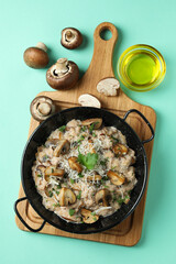 Concept of tasty food with risotto with mushrooms on mint background