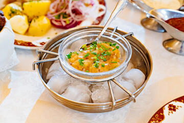 salted fish roe with green onions on a special metal dish with ice. cooling utensils. table setting. safe food serving.
