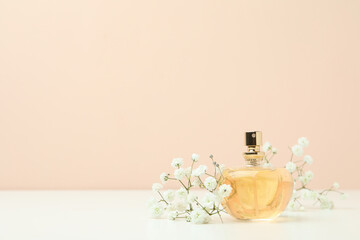 Perfume and flowers against beige background, space for text