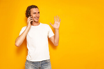 smiling man is talking on phone gesticulating with his raised hand, enjoying communication, dressed...