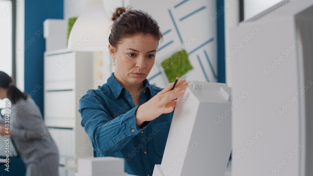 Poster portrait of woman engineer analyzing building model and structure to design construction plan. close