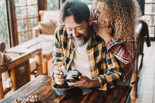 Happy adult couple at home looking camera pictures together with fun and smile. Concept of joyful lifestyle couple enjoying home. Hipster man and woman style hug in relationship and friendship