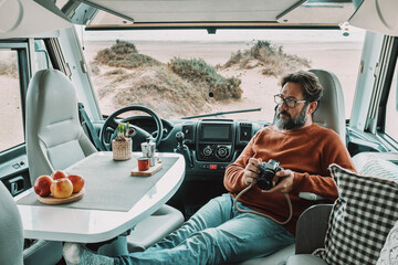 One man sitting and relaxing inside a camper van motor home dinette. Vanlife lifestyle and travel modern people. Holiday vacation with van for alternative tourist and explorers. Beach view