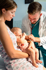 Pediatrician doctor medical examining little smiling baby, held by mother