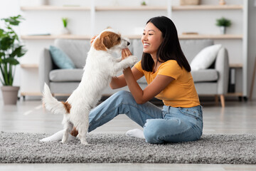 Cheerful asian woman training her dog, giving treats