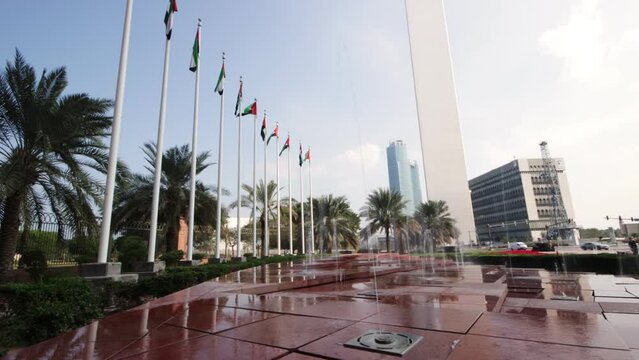 Square with water fountains and United Arab Emirates flags in Abu Dabi