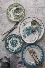 antique ceramic vintage plates and cutlery on a gray textured background