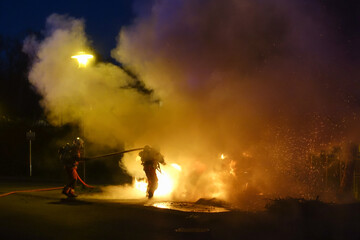 Des pompiers qui éteignent le feu de voitures garées