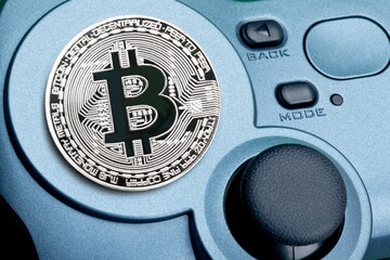 Crypto gaming concept. Video game controller with a bitcoin cryptocurrency coin on a background