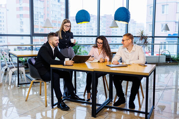 Meeting of business people, discussing new business ideas, using diagrams, sitting together. Modern office background. Meeting of business partners at a business development conference