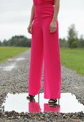 Unrecognizable woman in pink and high heels standing on mirror