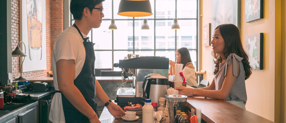 banner photo of Asian barista making coffee with coffee machine and serving a cup of cappuccino in...